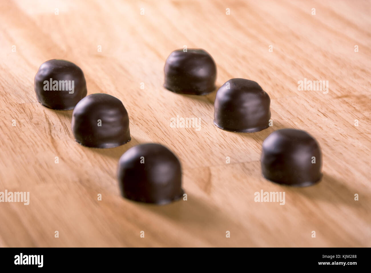 Juego de dark chocolate praliné bonbon sobre tabla de madera Foto de stock