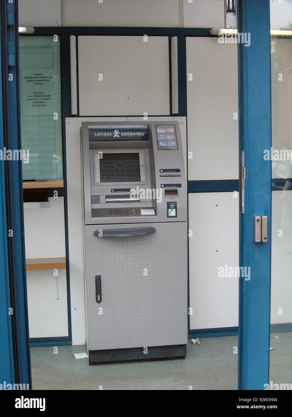 Liepaja, Letonia - Agosto 13, 2011: ATM o cajero automático está ubicado en la pequeña sucursal de banco detrás de puertas de vidrio cerrado. Foto de stock