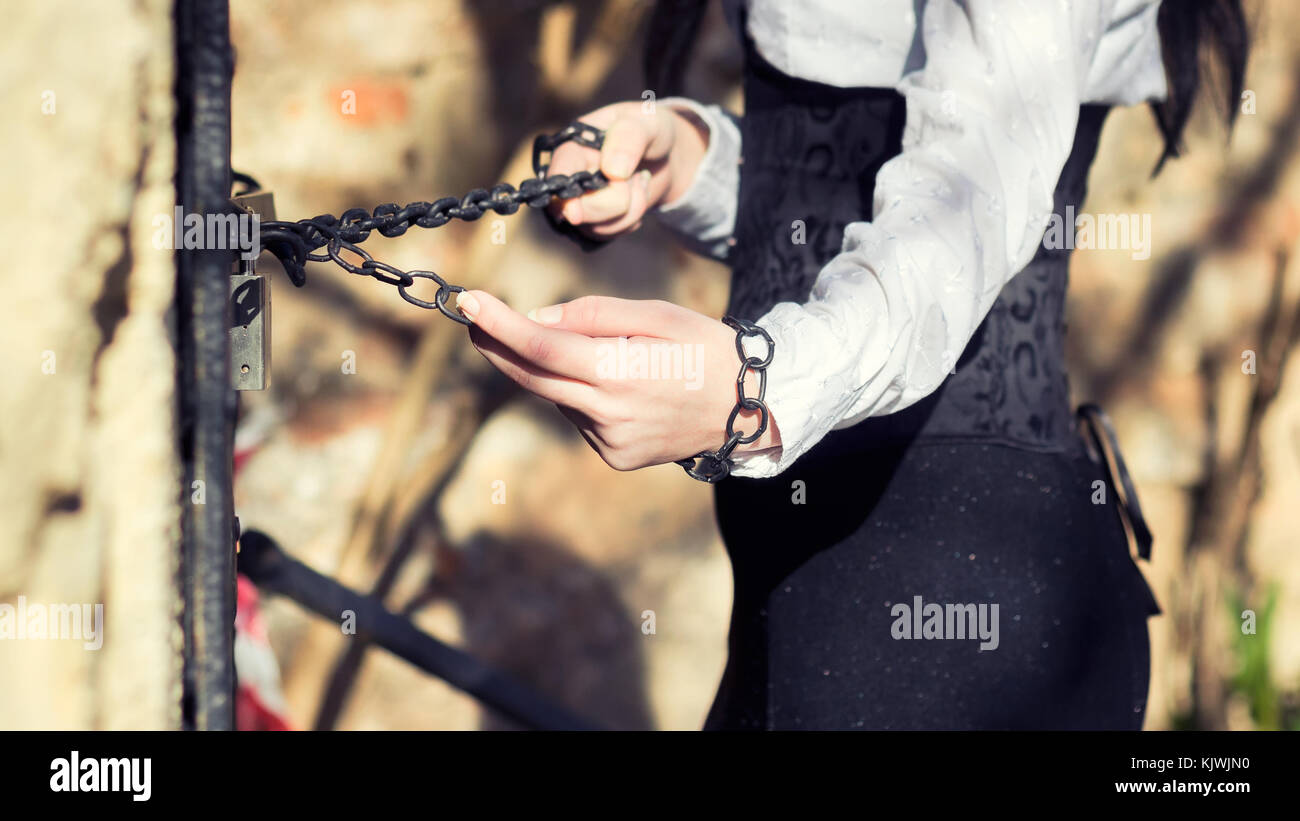 Mujer con la camisa blanca y el vestido negro, manos tirando de las cadenas  Fotografía de stock - Alamy