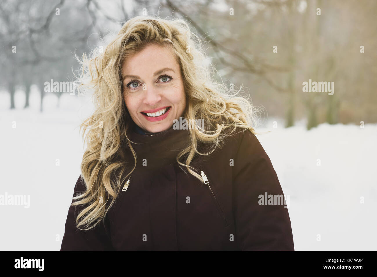 Mujer Invierno disfruta de un paseo por el parque cubierto de nieve Foto de stock