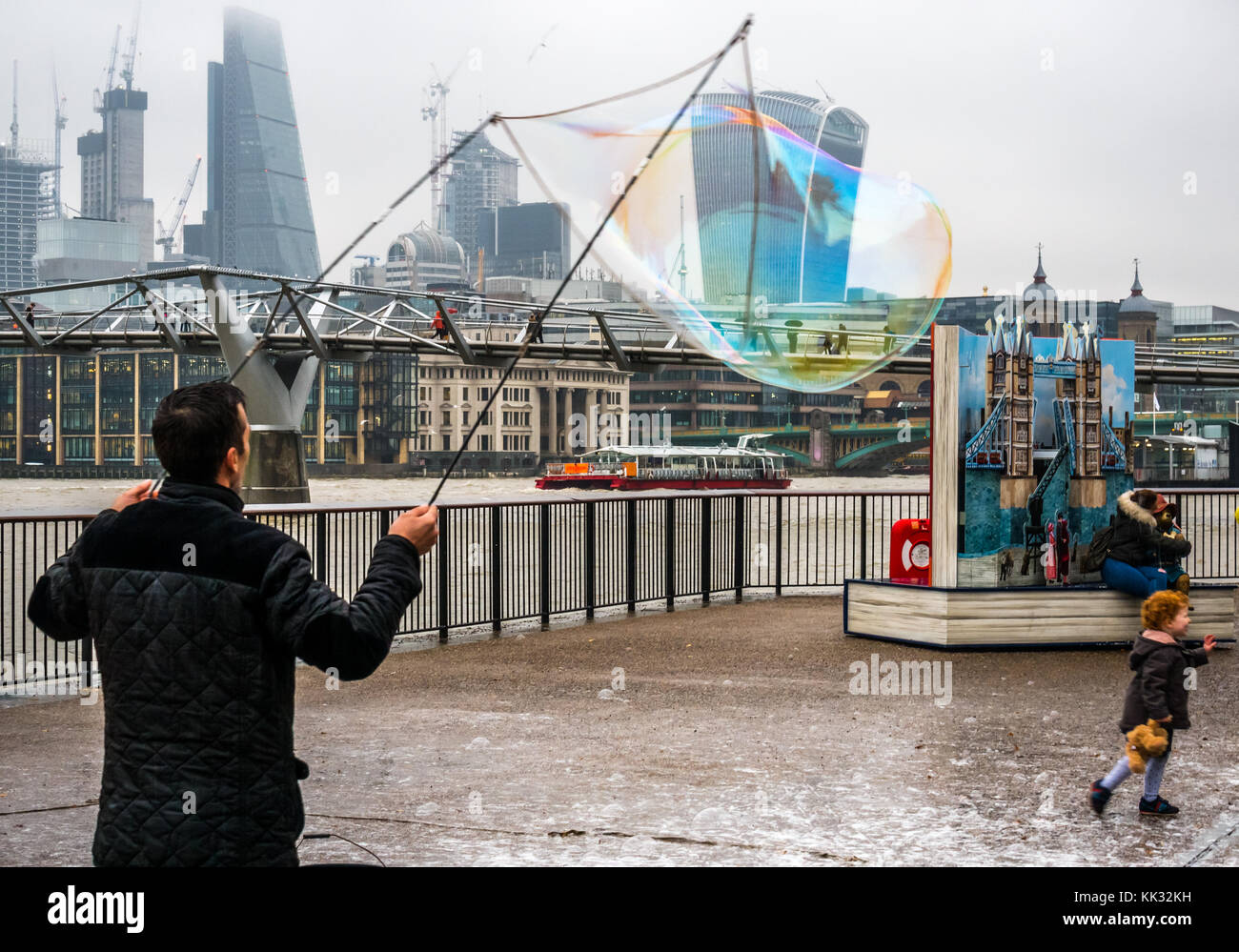 La orilla sur del río Támesis entretenido sendero, el hombre de los niños y las personas con burbujas, Londres, Inglaterra, Reino Unido con el Puente del Milenio y pop hasta Paddington bear Foto de stock