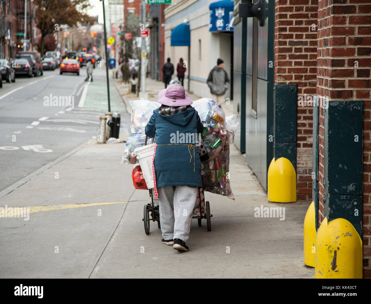 Una mujer empujando un carrito lleno de botellas y latas a un centro de reciclaje en Carroll gardens barrio de Brooklyn, Nueva York Foto de stock