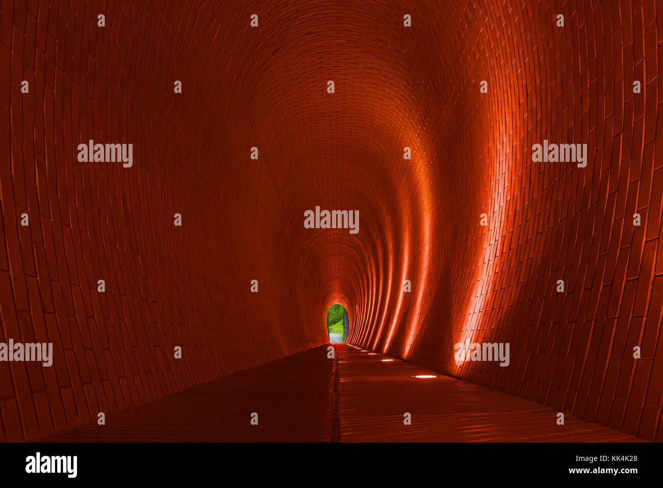 Vacía arcos en ladrillo largo túnel peatonal, Praga. naranja de las paredes de ladrillo, tira de Iluminación lámpara de arco brillante. Metro misterioso sendero para el caminante Foto de stock