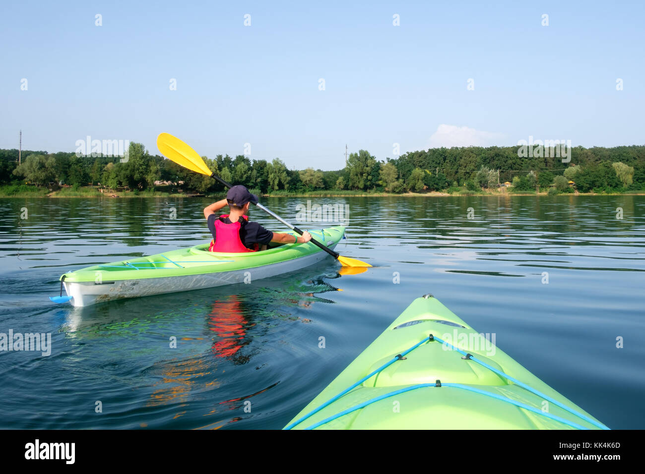 Muchacho de chaleco salvavidas kayak sobre verde Foto de stock