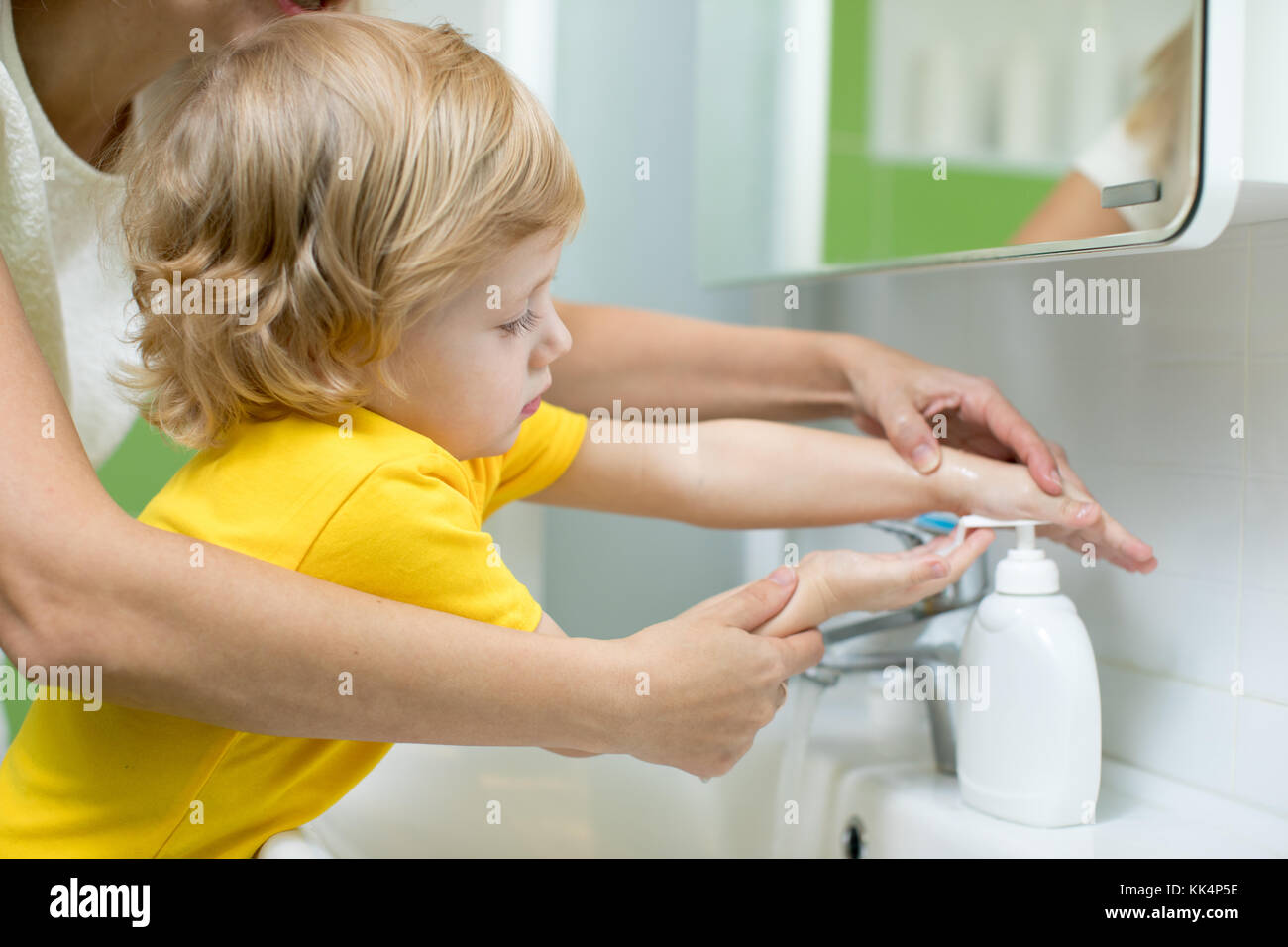 La madre y el niño, hijo de lavarse las manos en el baño. La atención y preocupación por los niños. Foto de stock