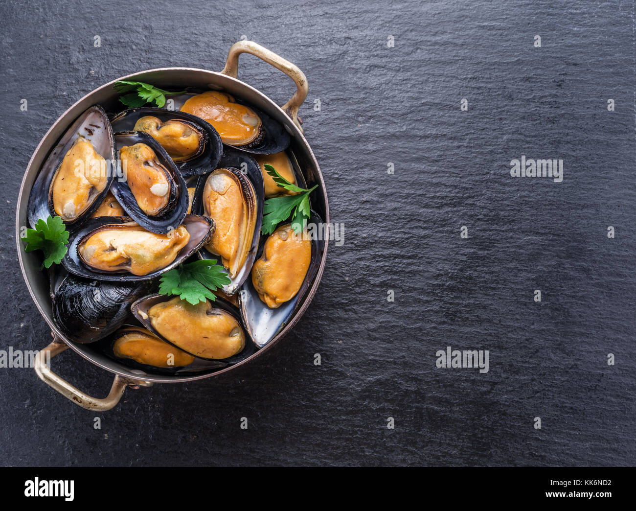 Mejillones hervidos en pan de cobre en el fondo de grafito. Foto de stock