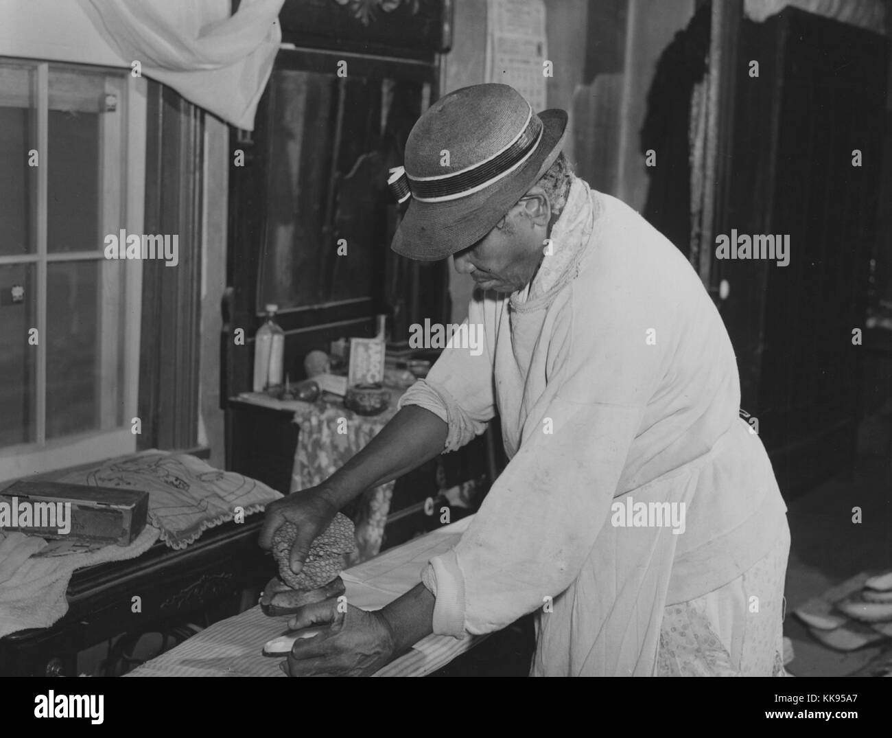 Fotografía en blanco y negro de un maduro afroamericana, Annie Albrittan, en una tabla de planchar, en su casa, Woodville, Greene County, Georgia, noviembre de 1941. Desde la Biblioteca Pública de Nueva York. Foto de stock