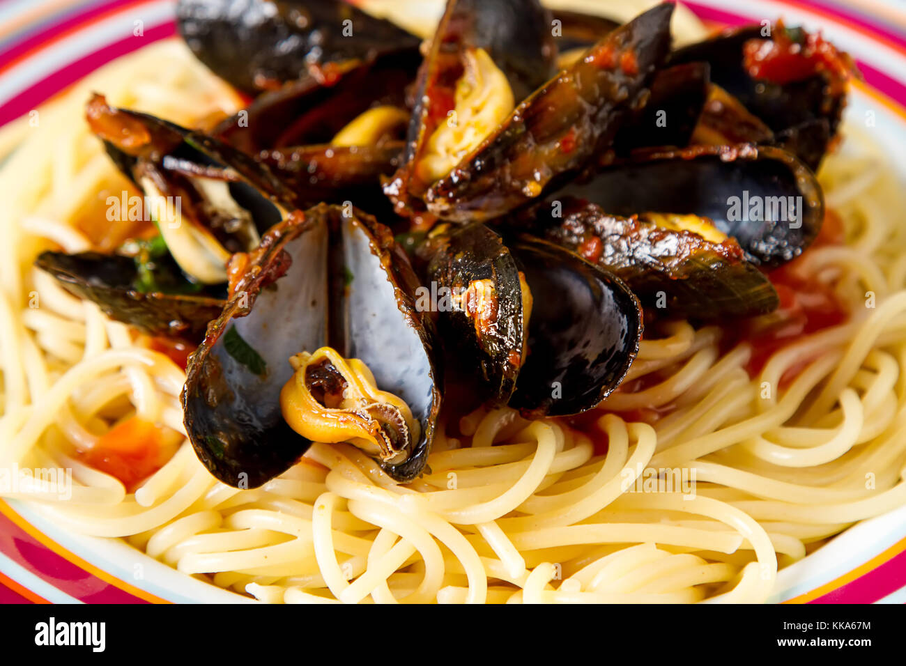 Espaguetis con mejillones con hierbas y salsa de tomate en un plato y mariscos. Comida en la orilla del mar francés. fondo oscuro Foto de stock