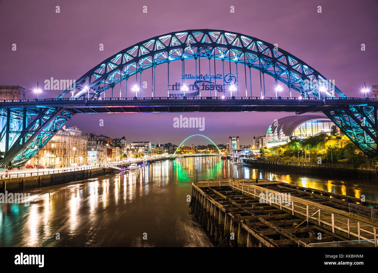 Foto nocturna mirando a lo largo del río Tyne hacia el puente Tyne y el puente Gateshead Millennium, Newcastle upon Tyne, Tyne y Wear, Inglaterra Foto de stock