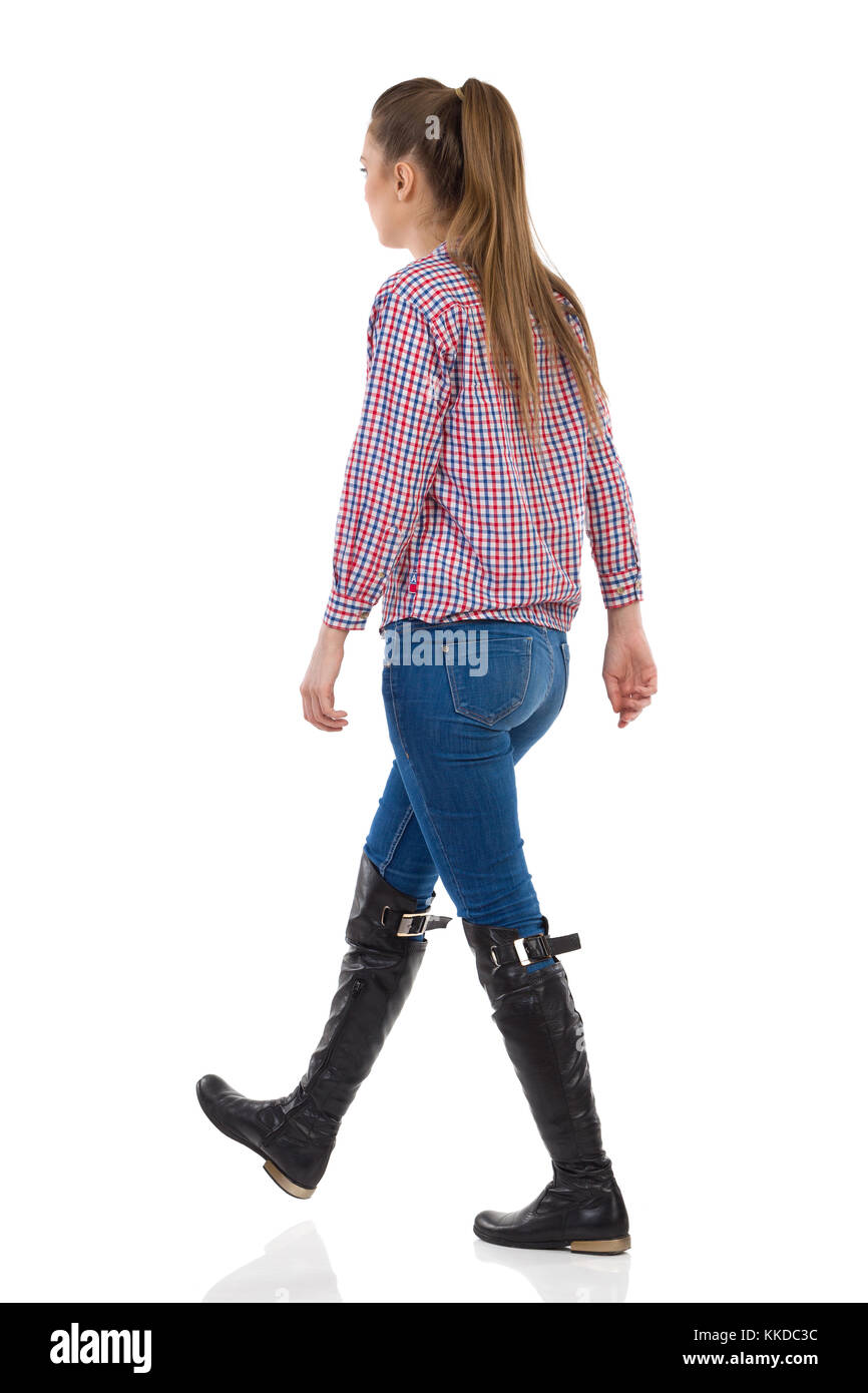 Mujer joven con el pelo largo en jeans, camisa negra y botas de leñador  caminando. Vista lateral trasera de longitud completa, Foto de estudio  aislado en blanco Fotografía de stock - Alamy