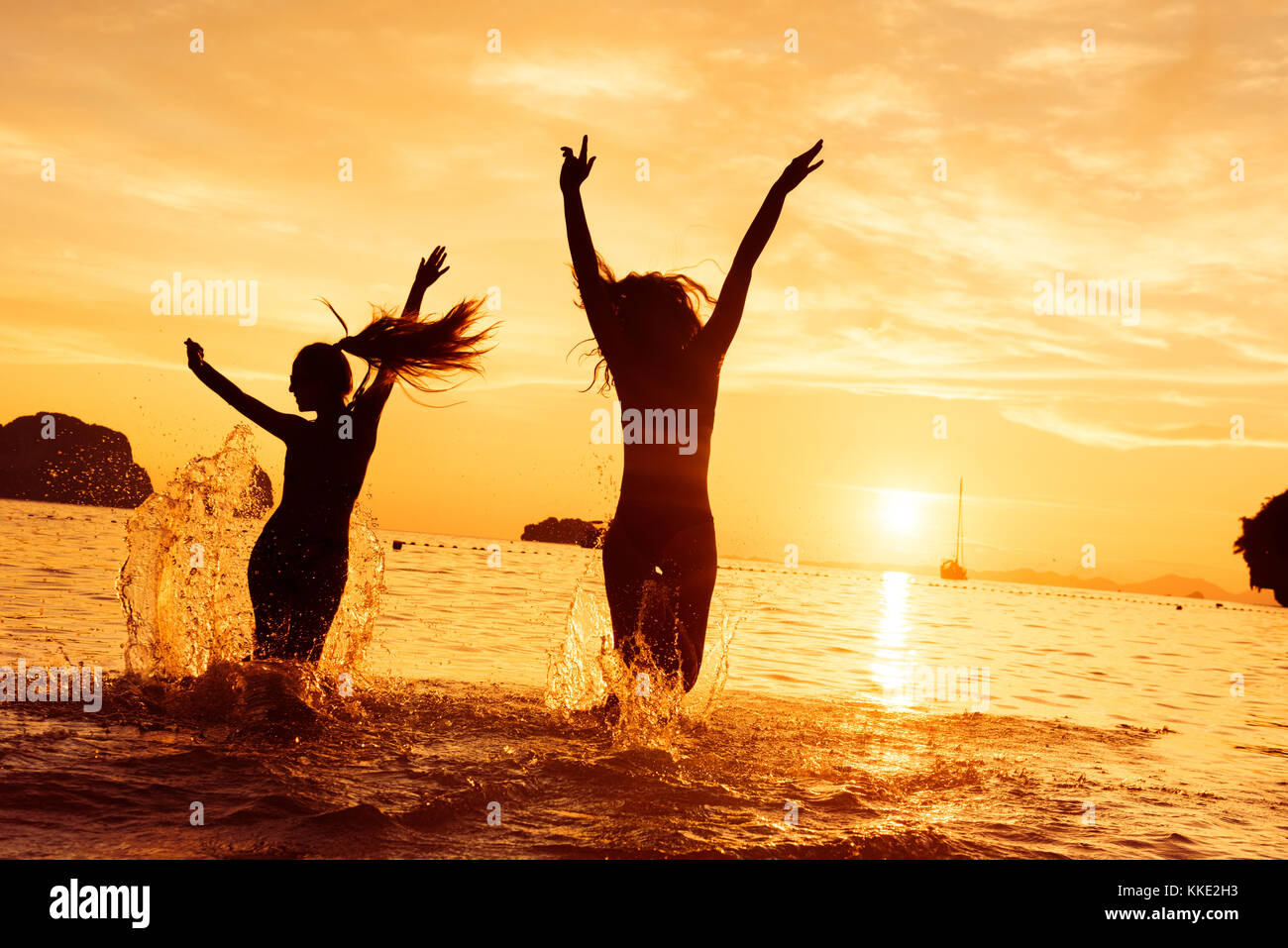 Dos niñas feliz corre a la mar al atardecer Foto de stock
