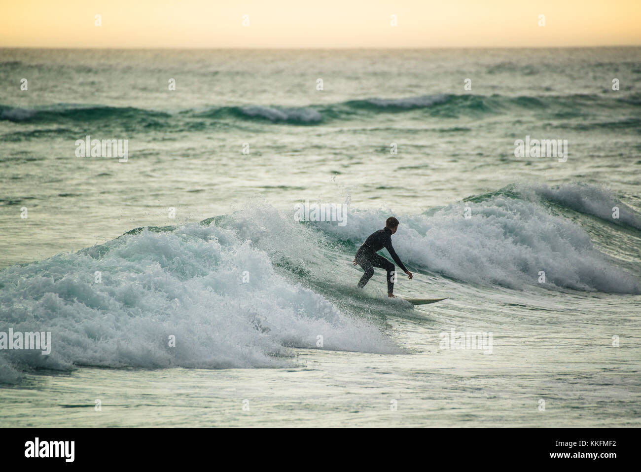 Surfer al atardecer, gran bahía, Ciudad del Cabo, Sudáfrica Foto de stock