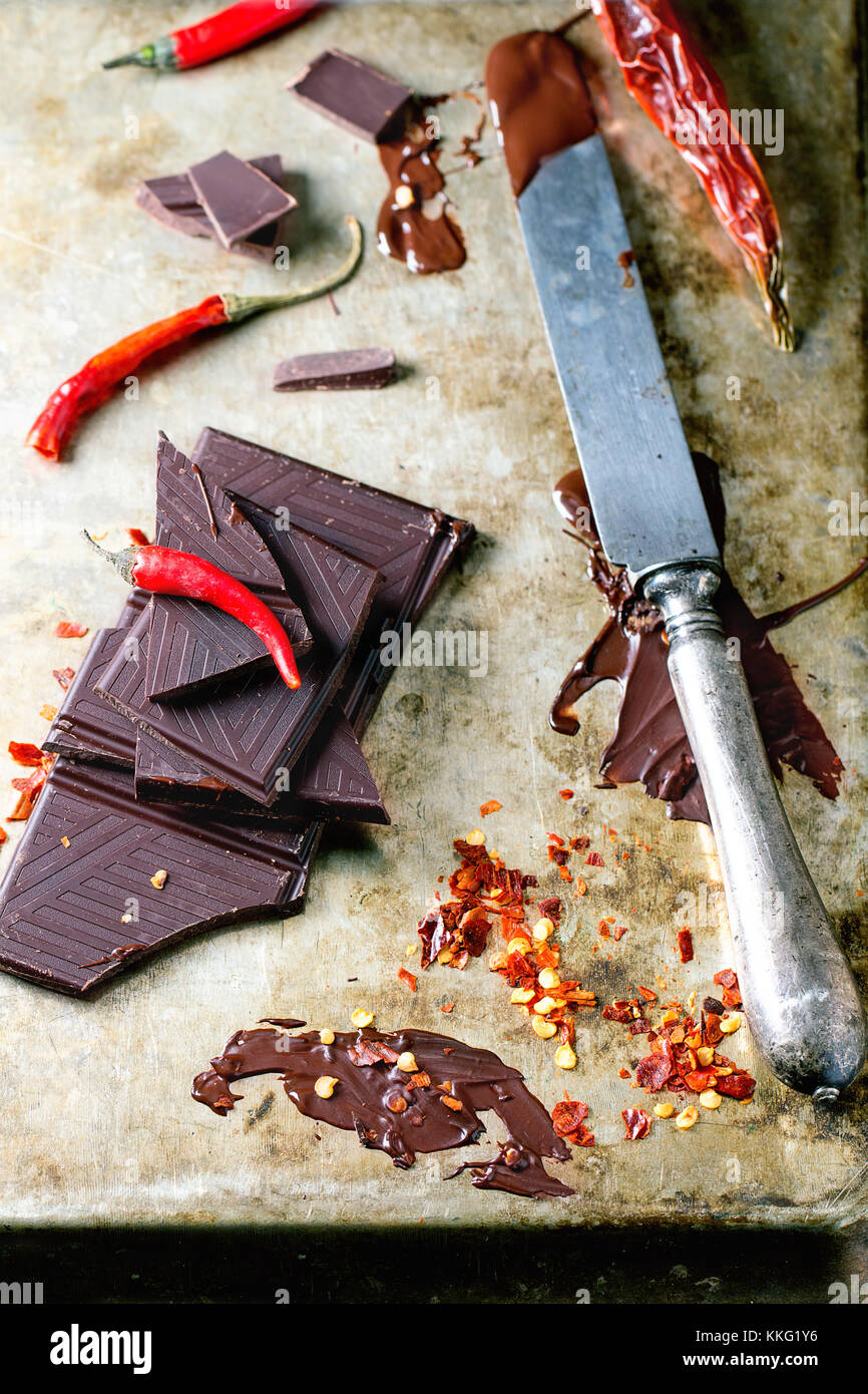 Picar y derritiendo el chocolate oscuro con fresco y seco de red hot chili  peppers y vintage cuchillo más antiguo fondo de metal Fotografía de stock -  Alamy