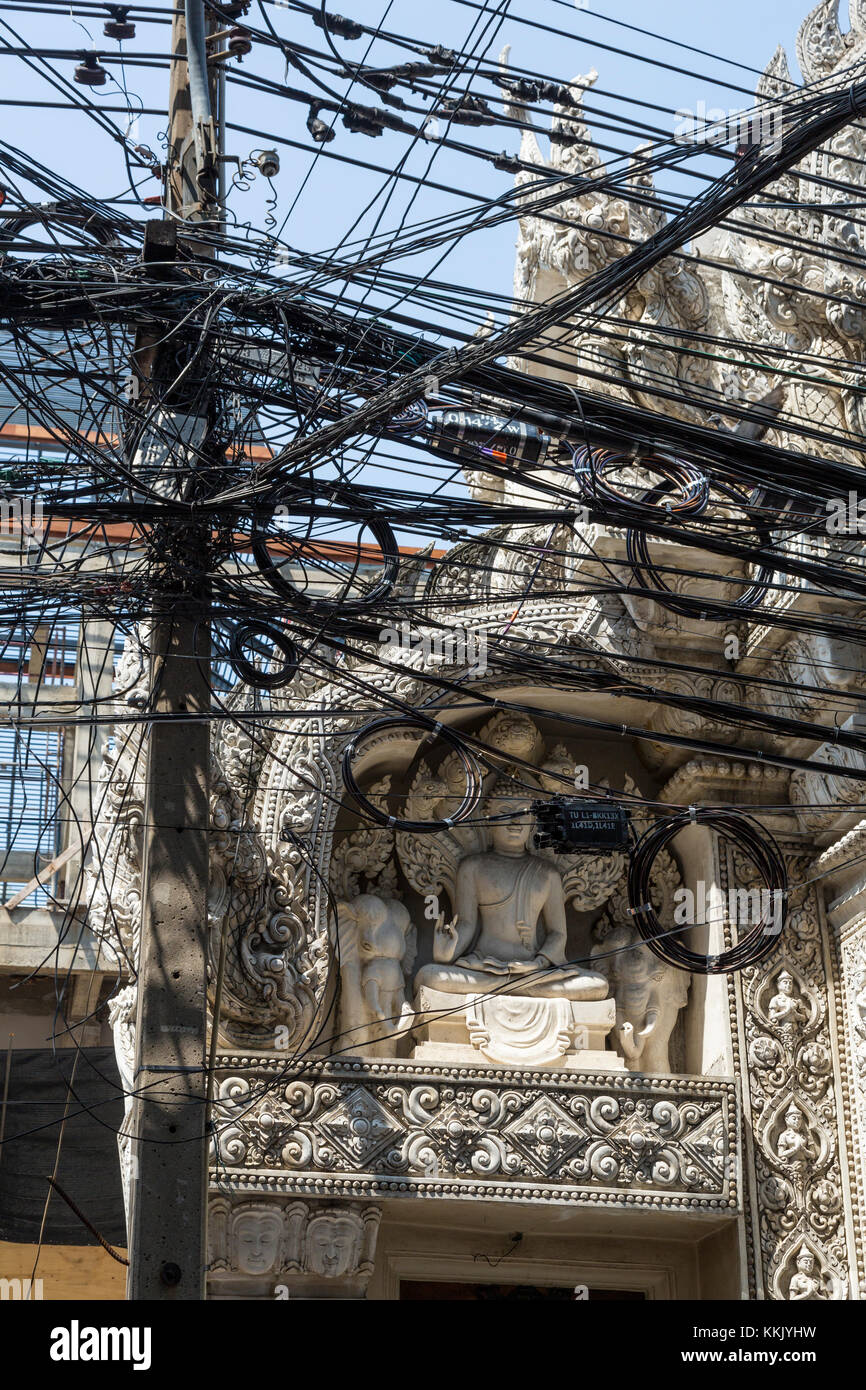 Bangkok, Tailandia. Líneas de transporte de energía eléctrica en la parte delantera de un santuario budista en Chinatown. Foto de stock