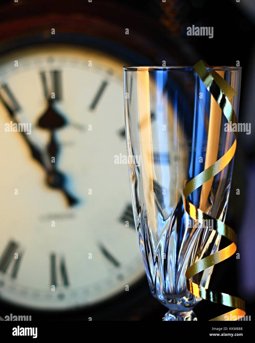 Reloj de año nuevo en el fondo con el vaso vacío y serpentinas Foto de stock