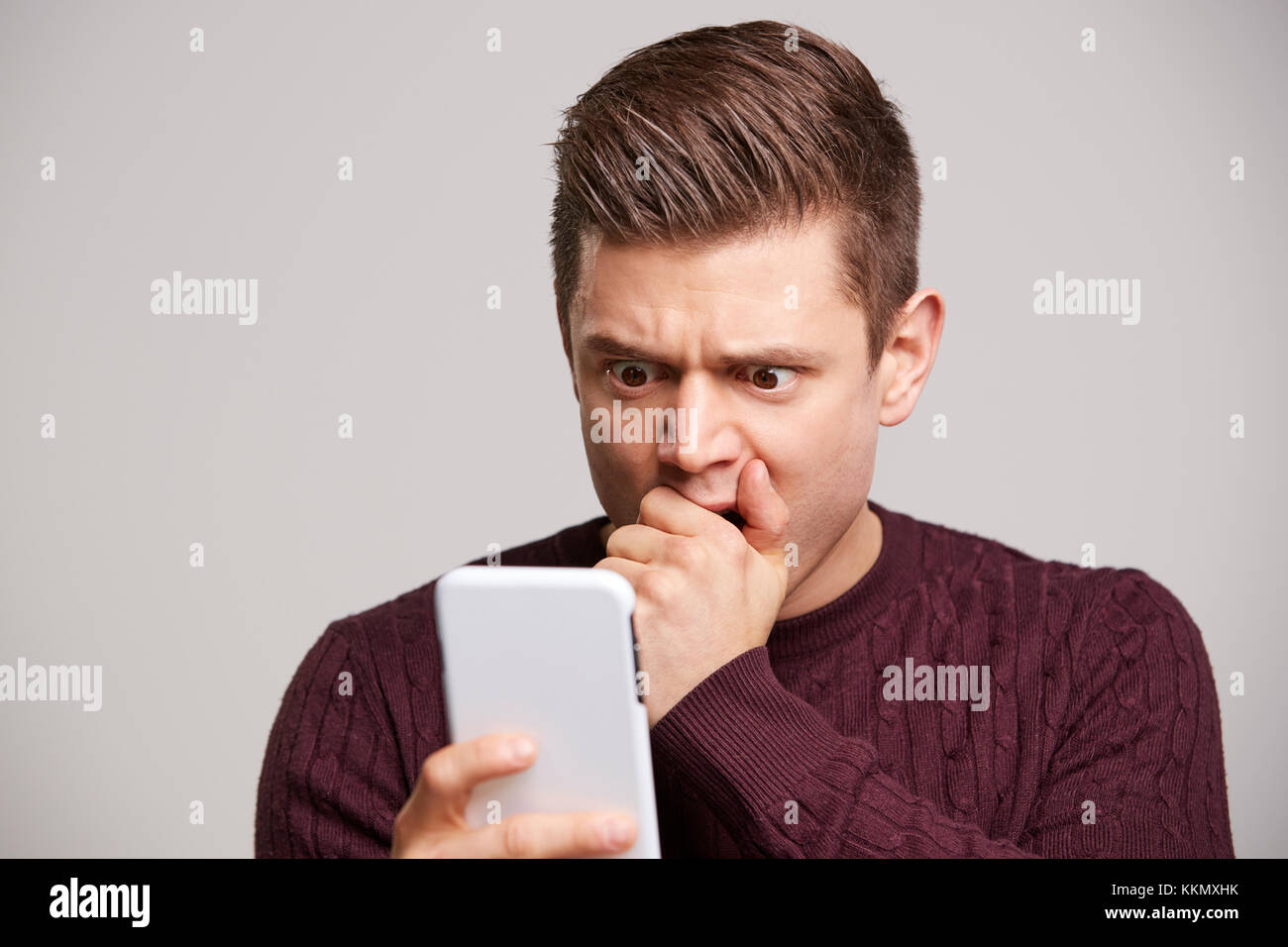 Retrato de un joven blanco conmocionado utilizando un smartphone Foto de stock
