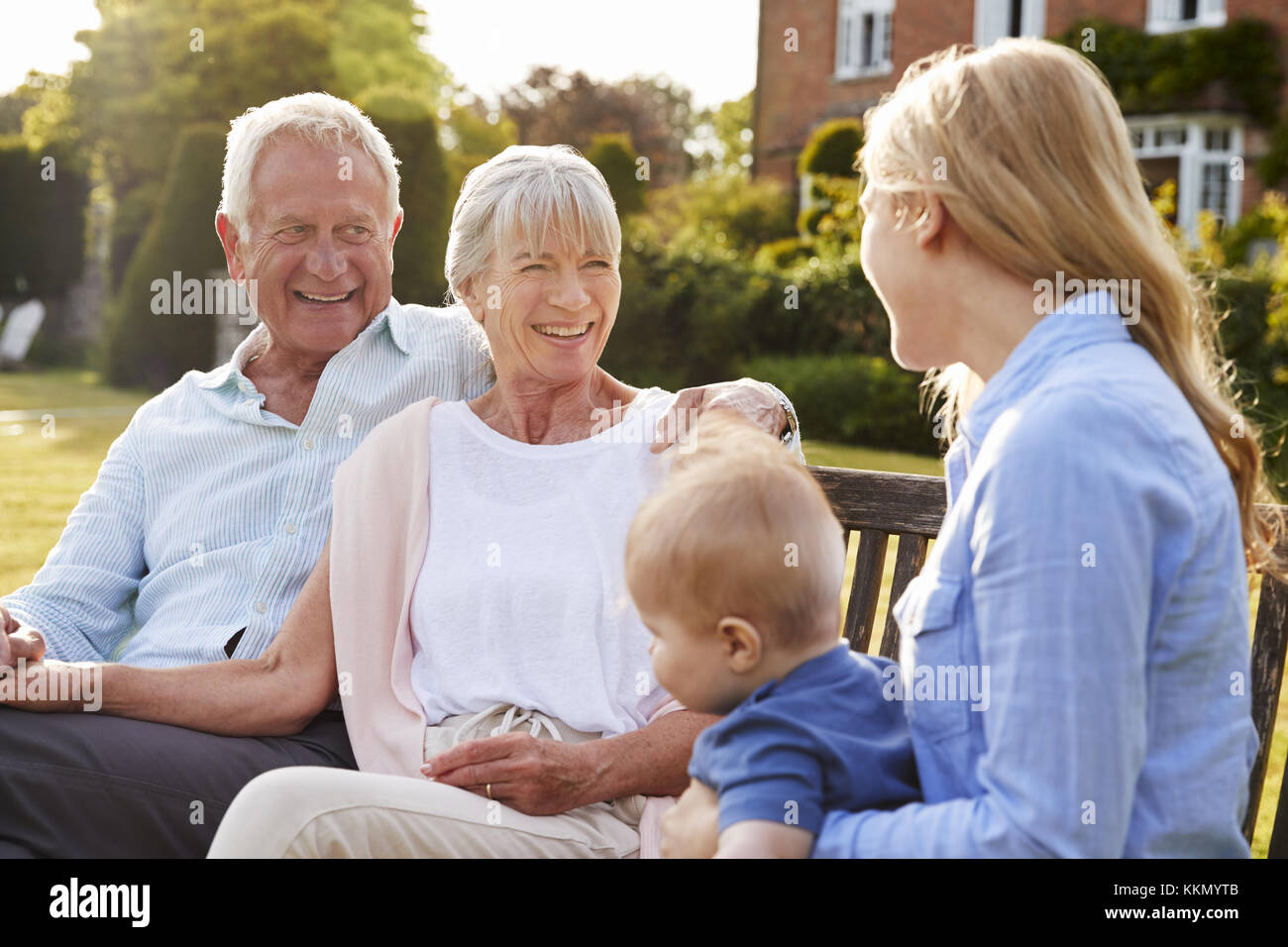 Los abuelos sentarse al aire libre con el bebé Nieto e hija adulta Foto de stock
