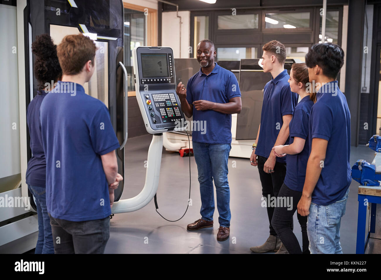 Ingeniero aprendices mostrando cómo utilizar la máquina de fabricación de herramientas CNC Foto de stock