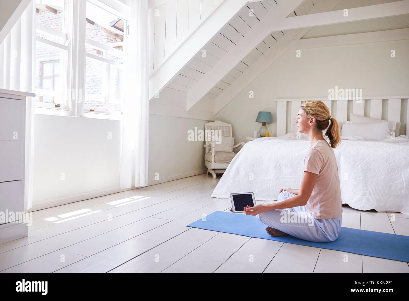 Mujer con tableta digital utilizando la meditación App en dormitorio Foto de stock