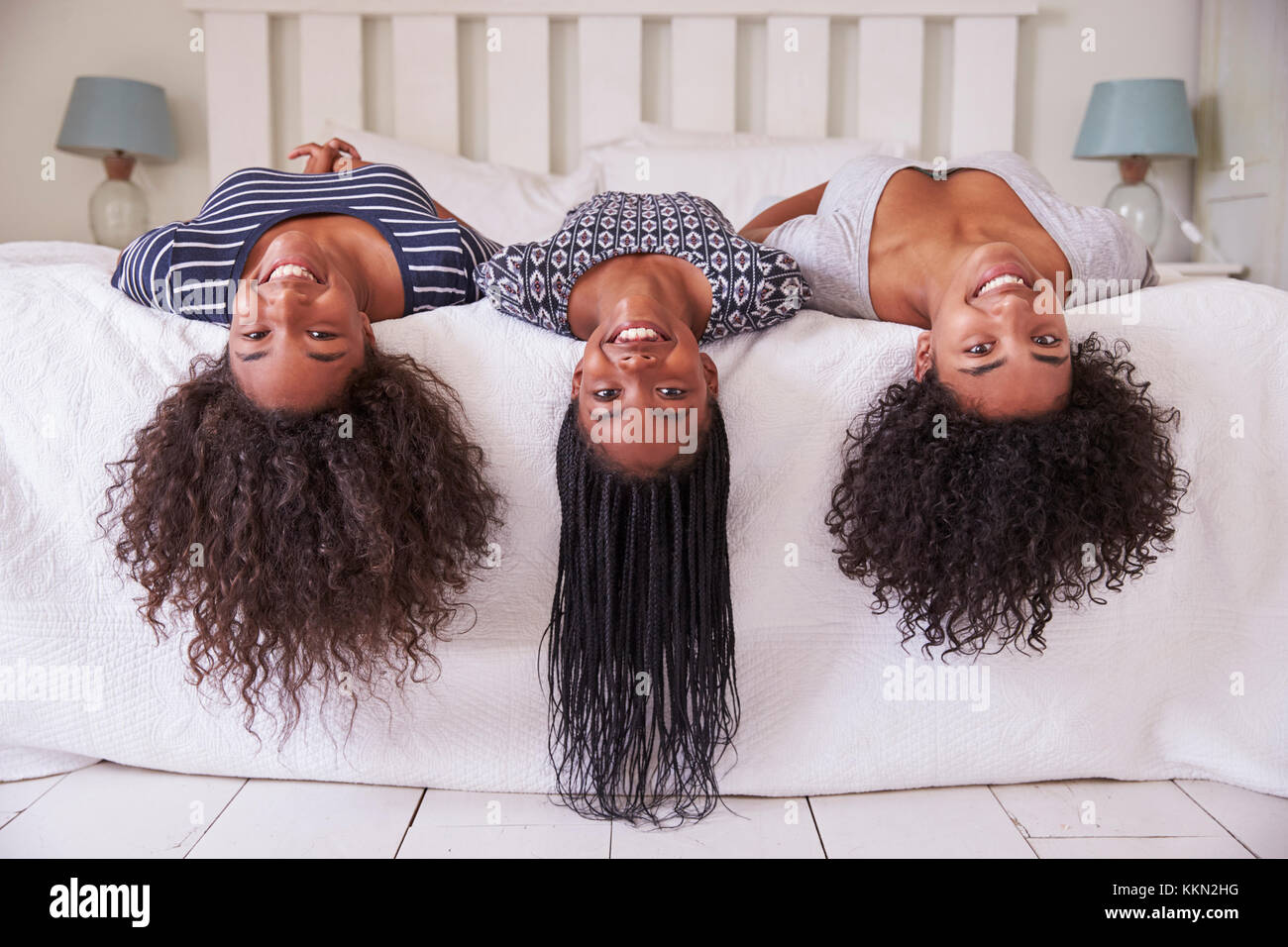 Tres hermanas adolescentes con pelo largo tumbado en la cama en casa Foto de stock