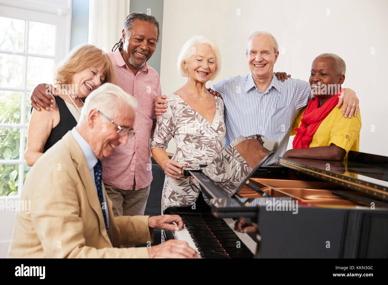 Grupo de ancianos de pie por Piano y cantando juntos Foto de stock