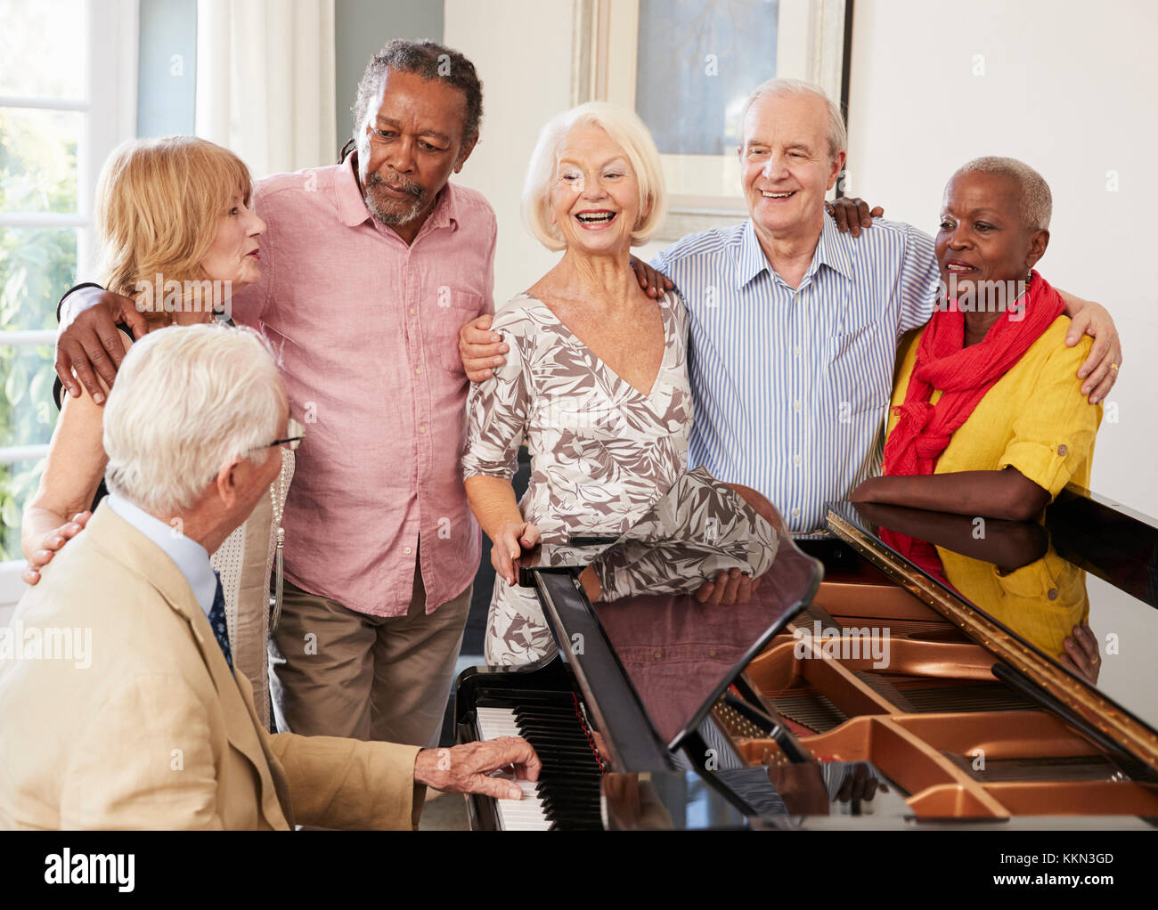 Grupo de ancianos de pie por Piano y cantando juntos Foto de stock