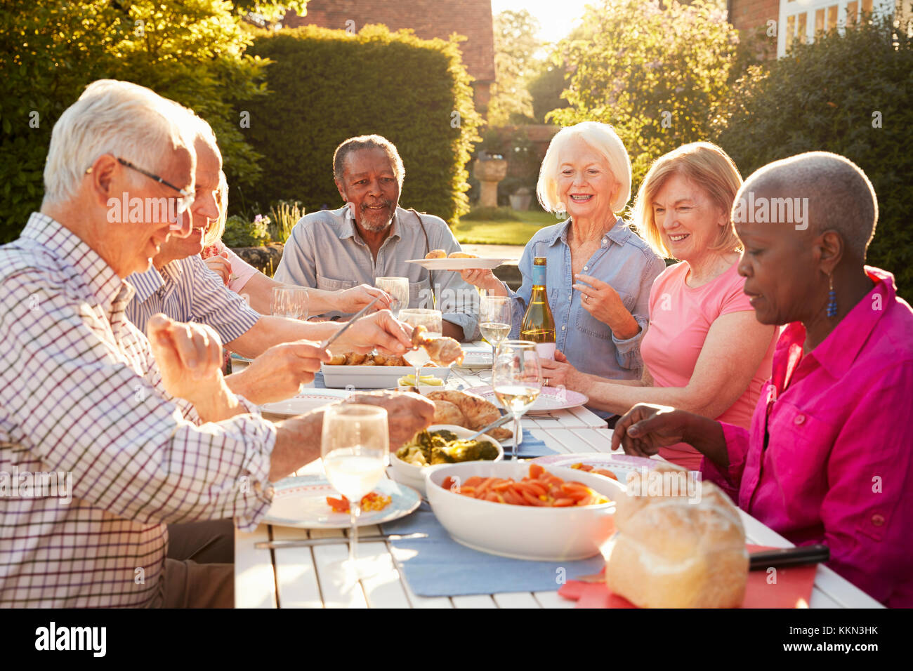 Grupo de Altos amigos disfrutando de la cena al aire libre fiesta en casa Foto de stock