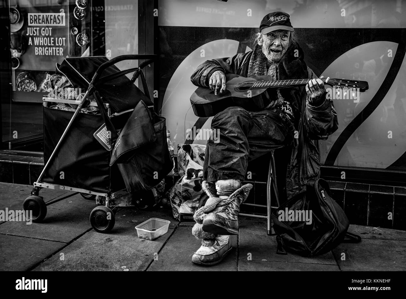 Hombre sin hogar Busking en la calle con sus pertenencias en el centro de la ciudad de Manchester, Inglaterra, Reino Unido. Foto de stock