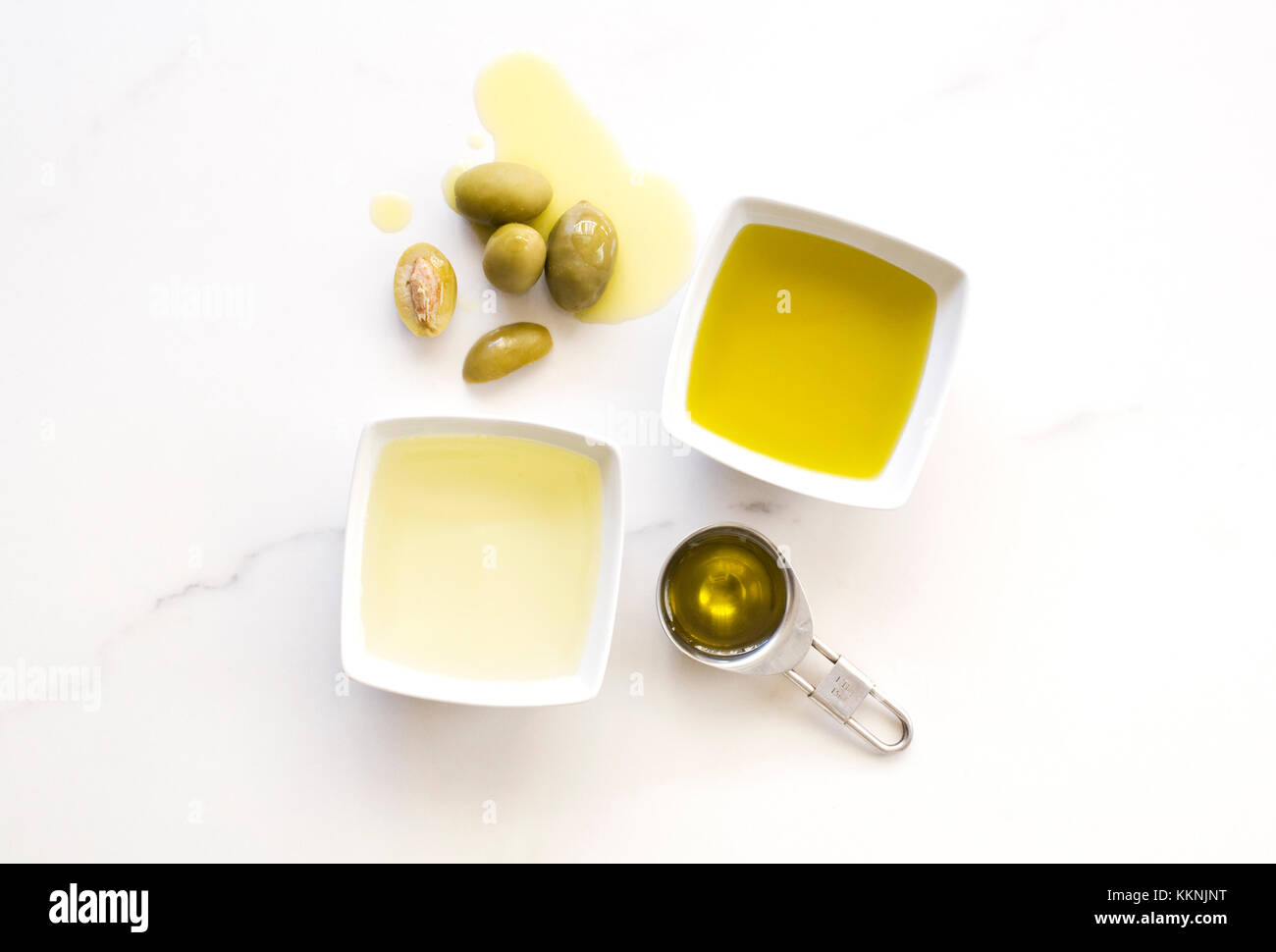 Los aceites de oliva y aceitunas, sobre un fondo de mármol. Foto de stock