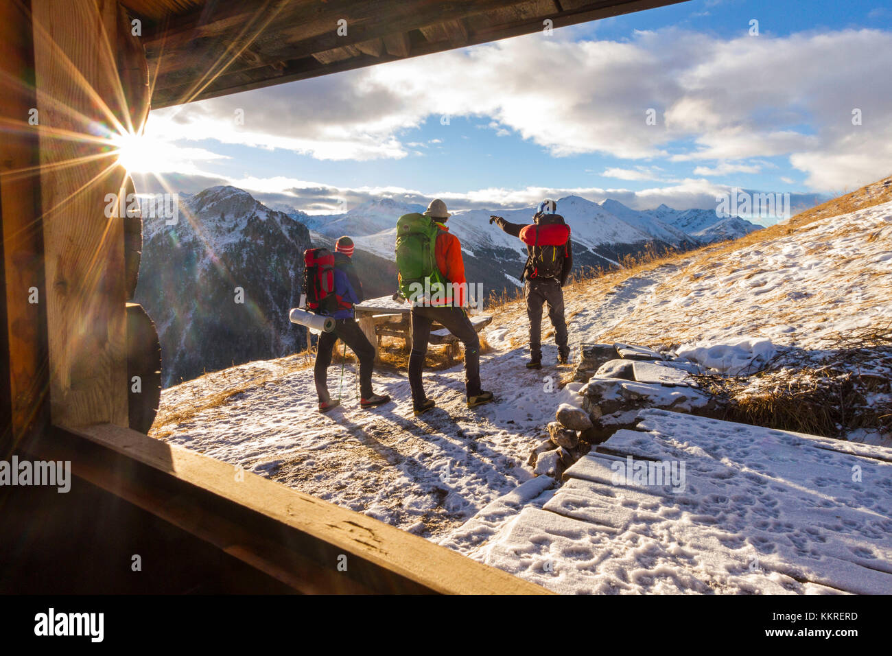 Excursionistas admirando el amanecer desde una cabaña alpina. Livigno, Valtellina, Italia Foto de stock