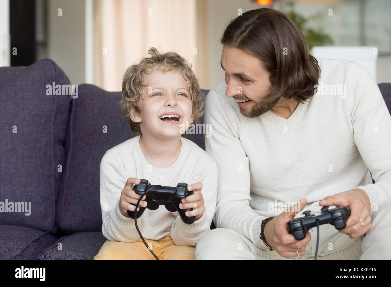 Jugar a videojuegos con padre hijo divertirse celebración controlle Foto de stock