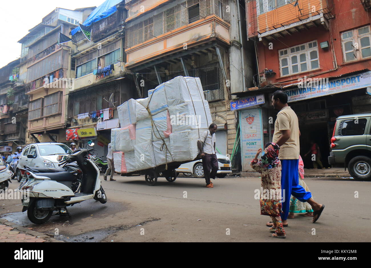 El hombre no identificado lleva pesado carro cargado en el centro de la ciudad de Mumbai, India. Foto de stock