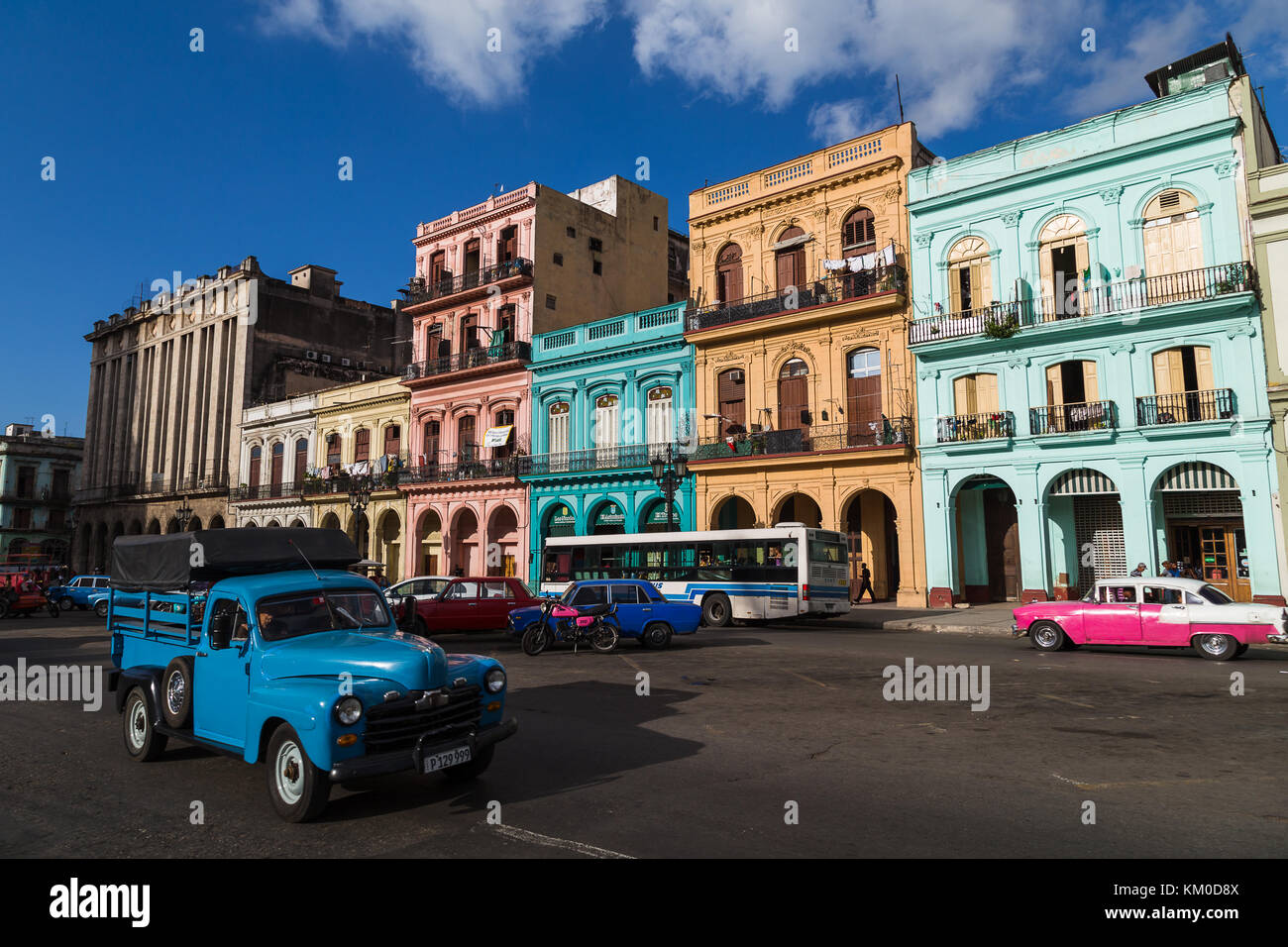 Una pequeña camioneta azul (originarias de América en los 50s) pasa una fila de edificios coloridos en el paseo del Prado, la calle principal que divide a l Foto de stock