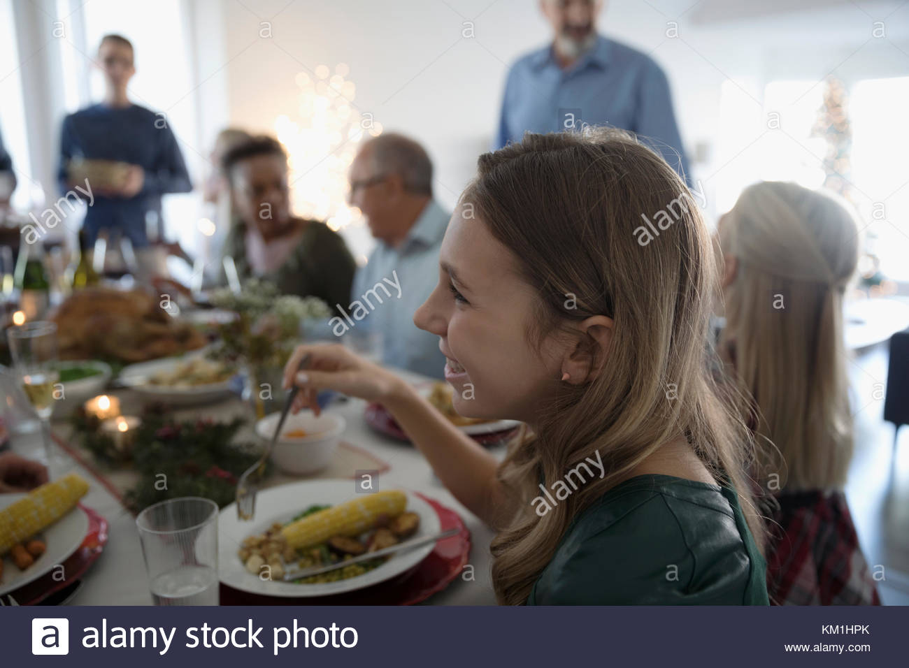 Chica sonriente disfrutando de la cena de Navidad de la familia en la mesa Foto de stock