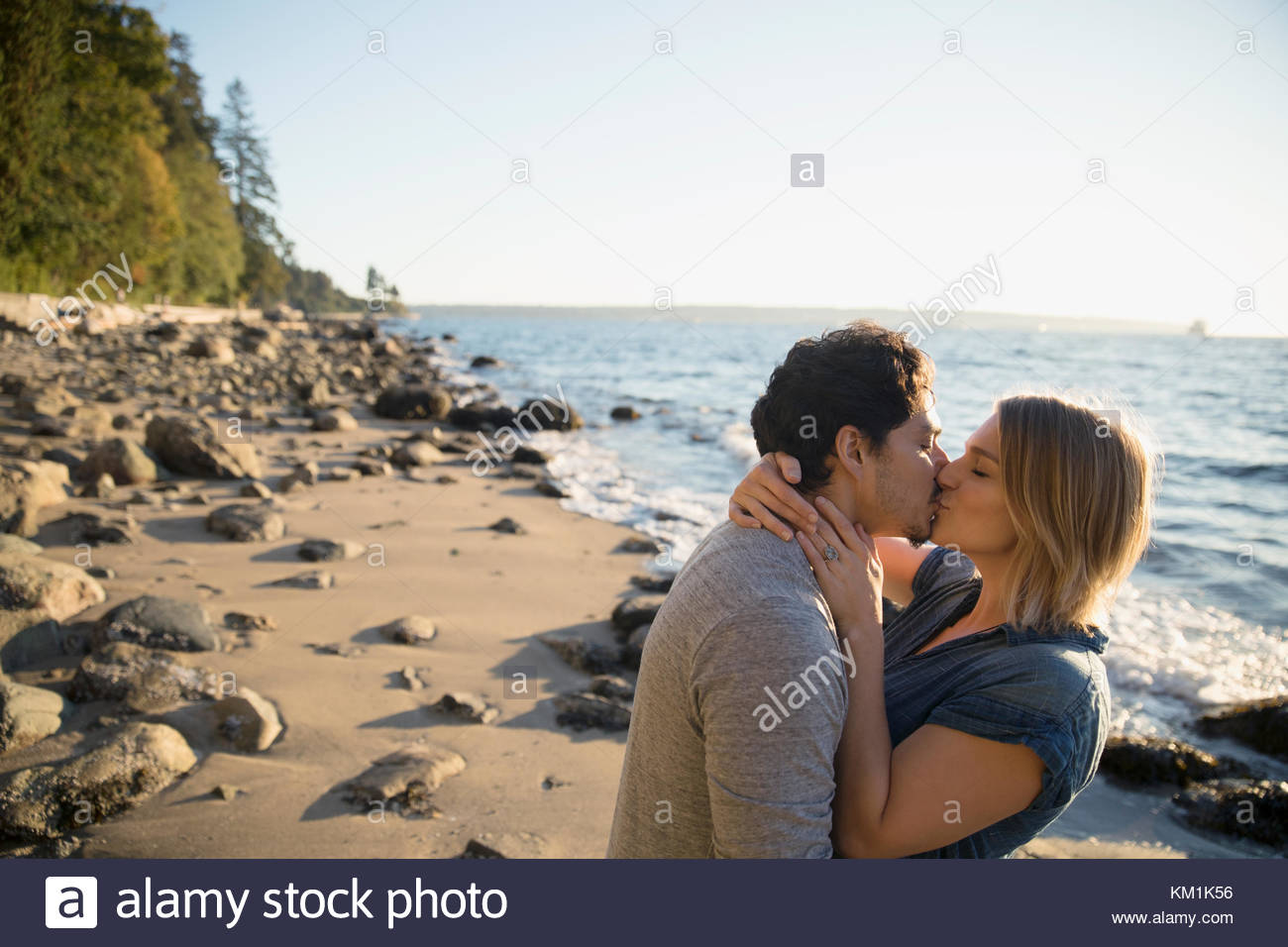 Afectuosa pareja besándose en la soleada playa. Foto de stock