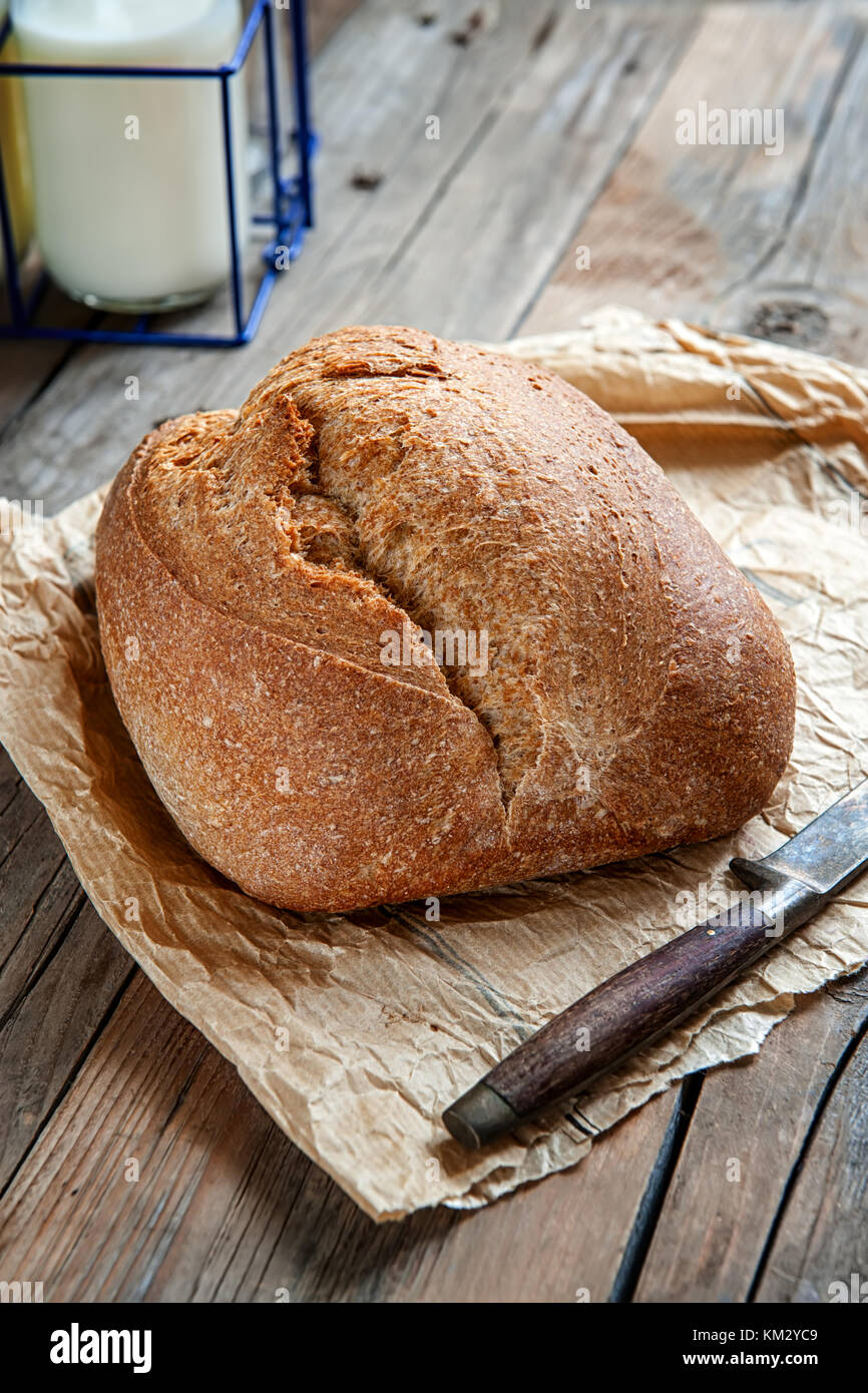 Una hermosa hogaza de pan de masa fermentada de trigo blanco en una placa en un borde de lino. Pasteles caseros. En un estilo rústico. Foto de stock