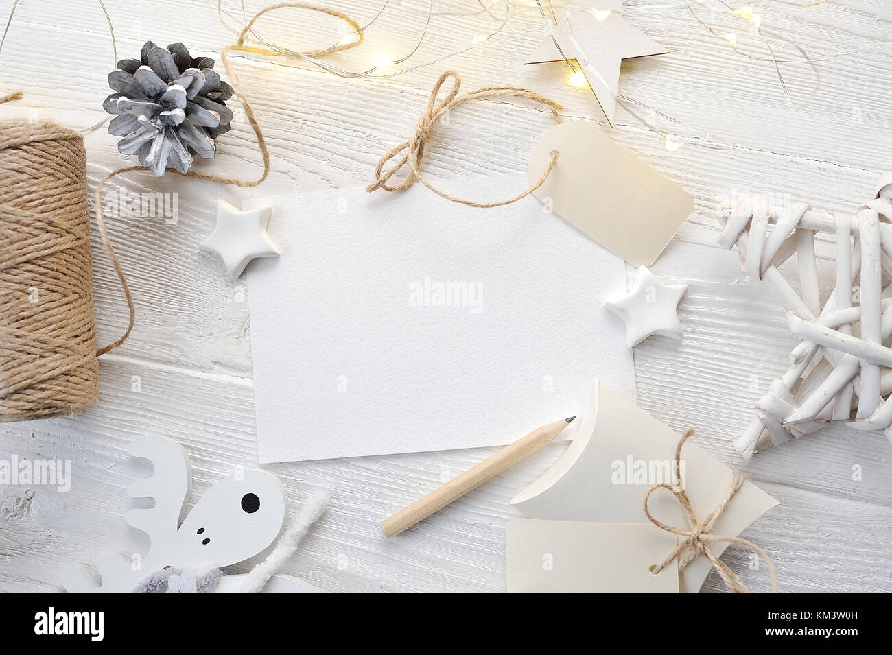 Tarjeta de felicitación de Navidad maqueta vista superior, flatlay sobre un fondo de madera blanca con una guirnalda Foto de stock