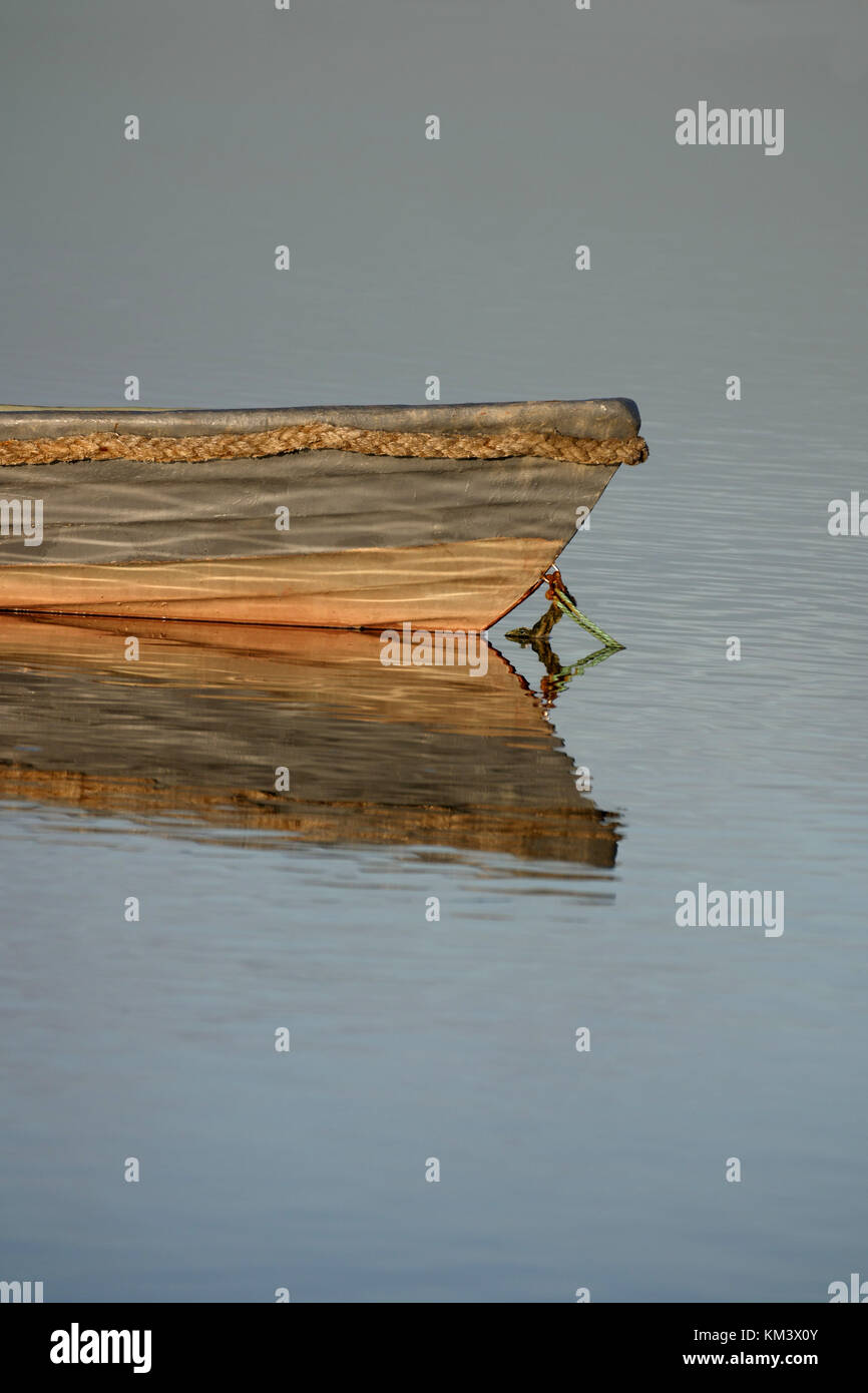 Barco de madera con una reflexión sobre el agua, los bancos de juncos en el fondo. Copie el espacio superior e inferior. Foto de stock