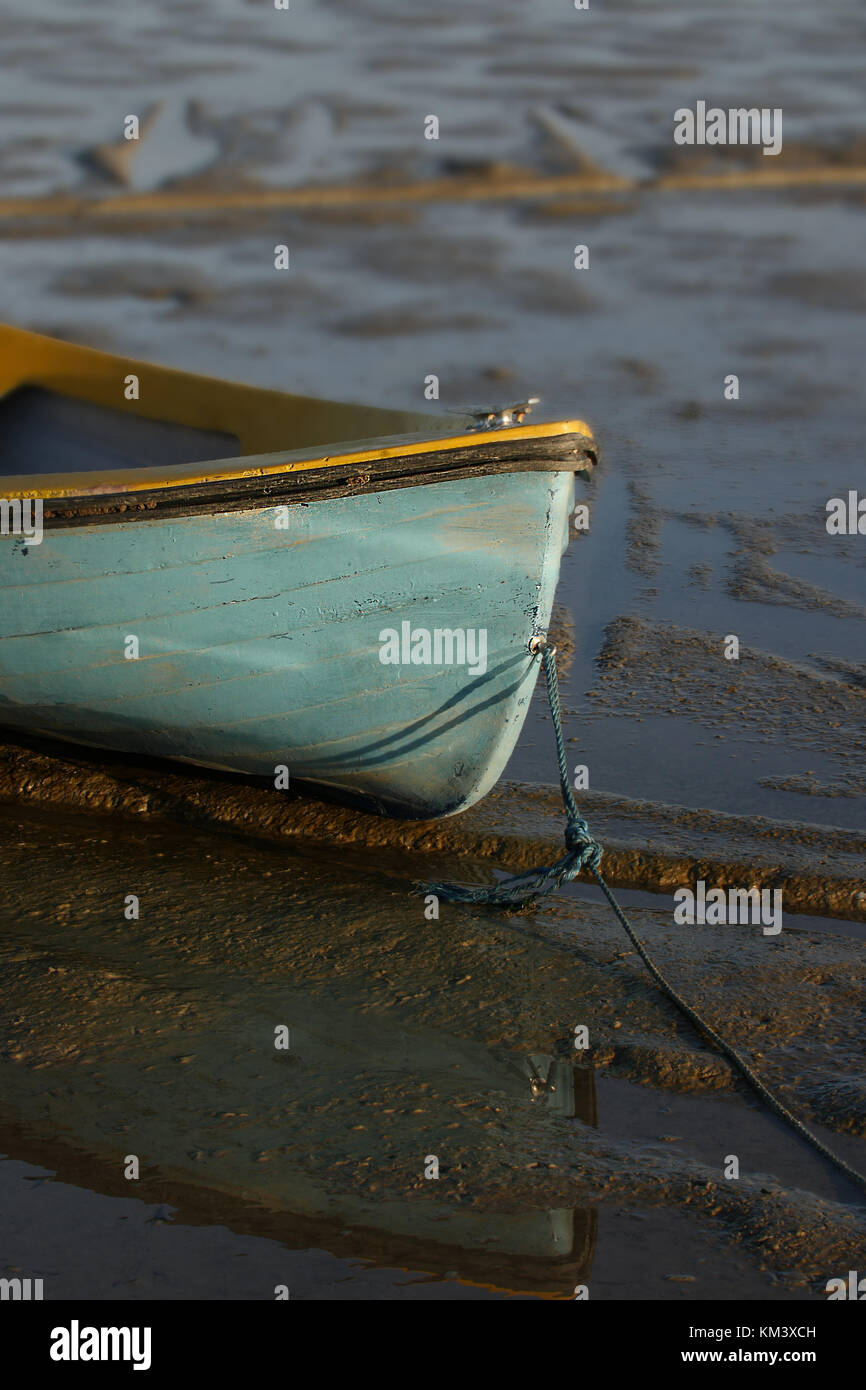 Barco de madera de color turquesa, amarrado en la marea baja. Foto de stock