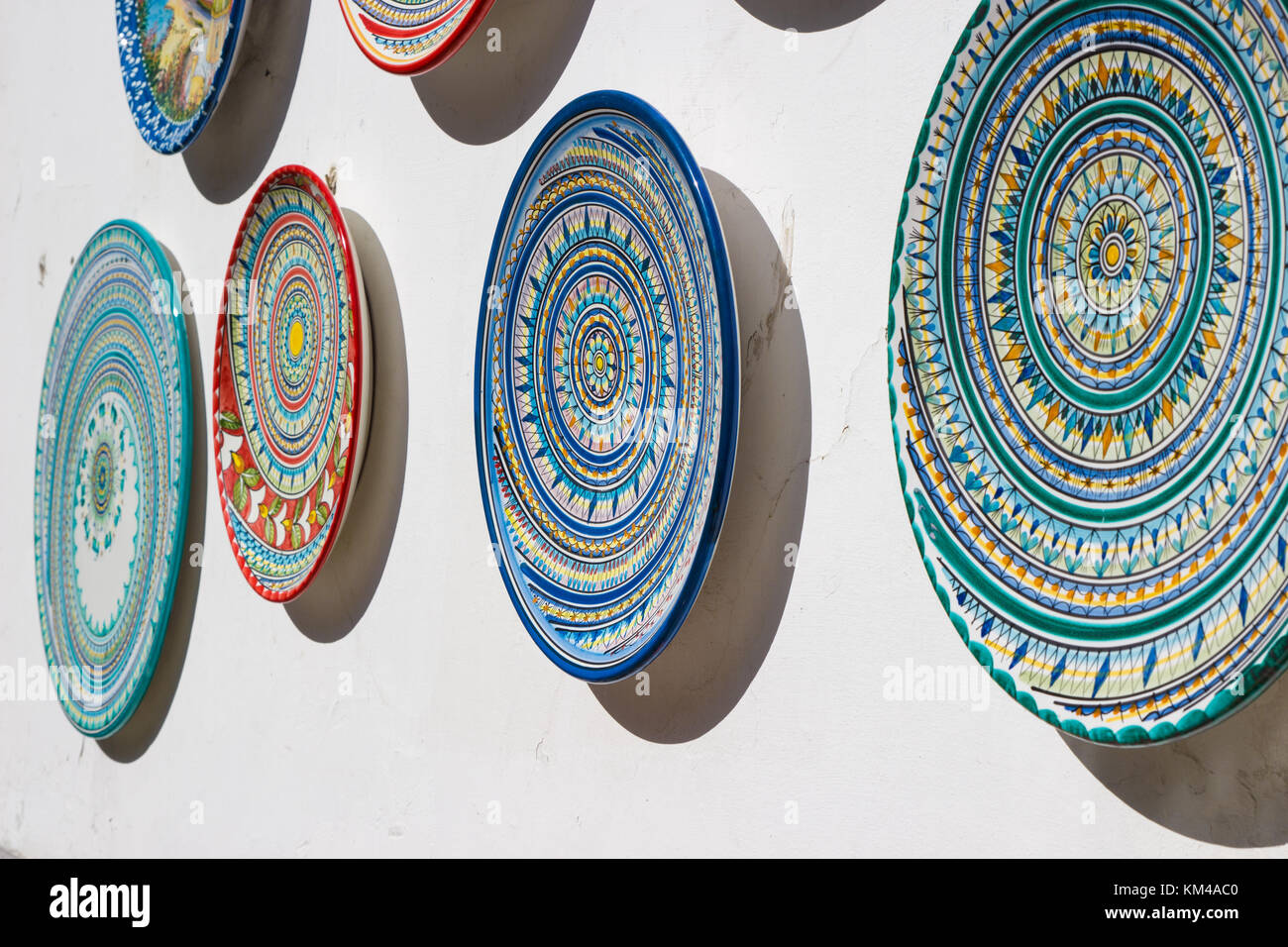 Diversos platos de cerámica decorada colgado a la venta fuera de una tienda de souvenirs en la costa de Amalfi, Italia. Foto de stock