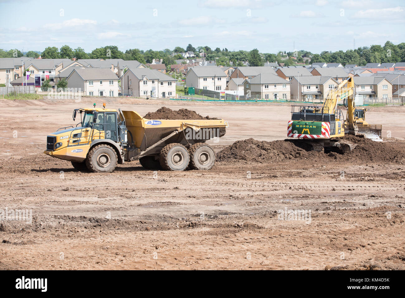 La construcción de viviendas en un sitio en Bishopton brownfield, Escocia mostrando nuevas casas, las tierras despejadas y excavadoras preparando el terreno Foto de stock