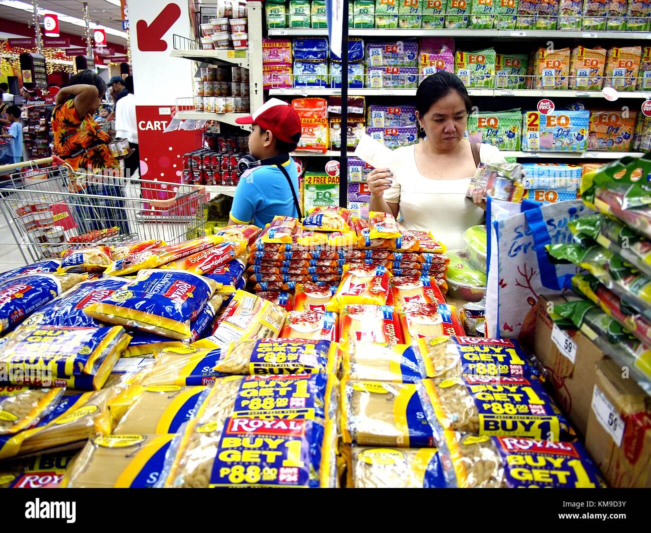 Antipolo City, Filipinas - Diciembre 2, 2017: una dama desprotege un producto de una pila de comestibles en un supermercado. Foto de stock