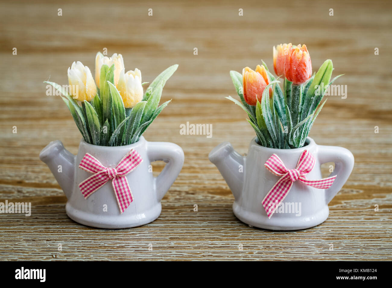 Tulipanes artificiales en macetas de porcelana blanca con tetera diseño y  Pink Ribbon sobre fondo de madera Fotografía de stock - Alamy