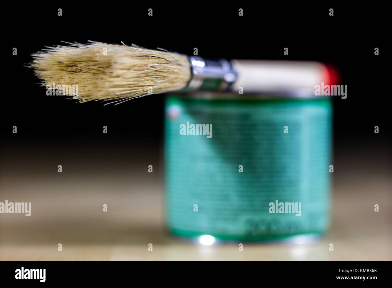 Pedzel para pintar con pintura de aceite en un taller de madera de tabla y  una lata de pintura. Un cepillo de púas en un taller. fondo negro  Fotografía de stock -