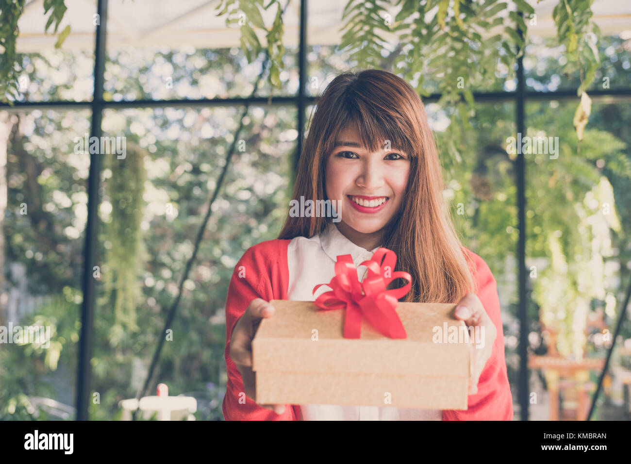 Joven mujer vestidos de rojo cardigan mantenga caja de regalo para un  hombre. mano dar presente cuadro. Navidad, fiesta de año nuevo. de San  Valentín, cumpleaños, aniversario celebrat Fotografía de stock -