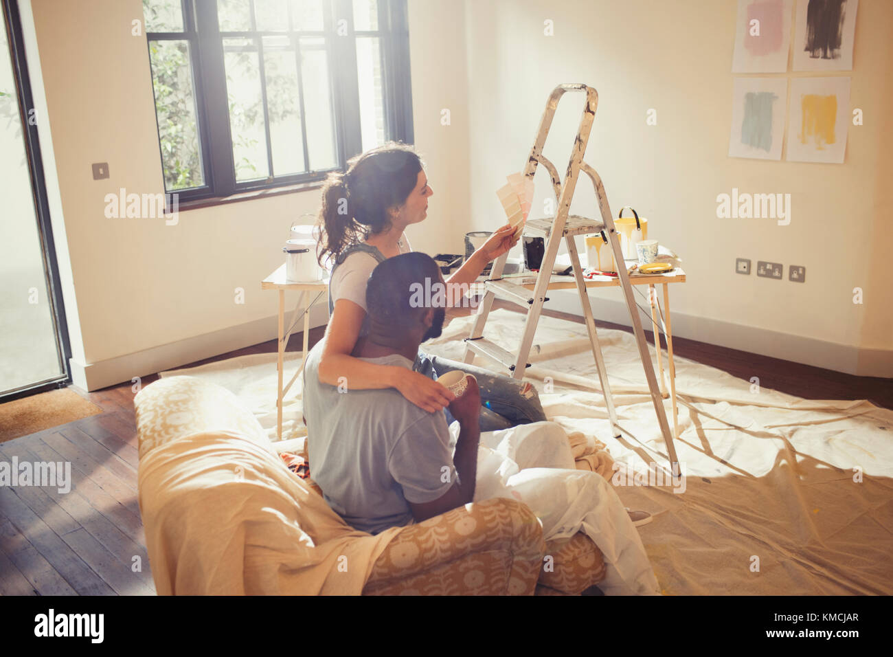Pareja joven viendo relojes de pintura, pintando sala de estar Foto de stock