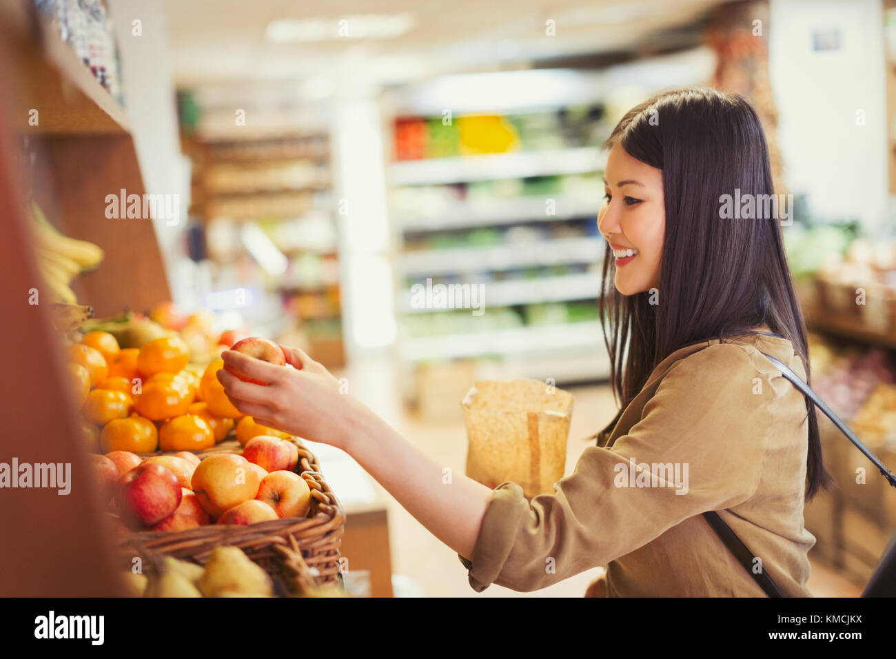 Sonriente mujer joven de compras de manzanas en la tienda de comestibles Foto de stock