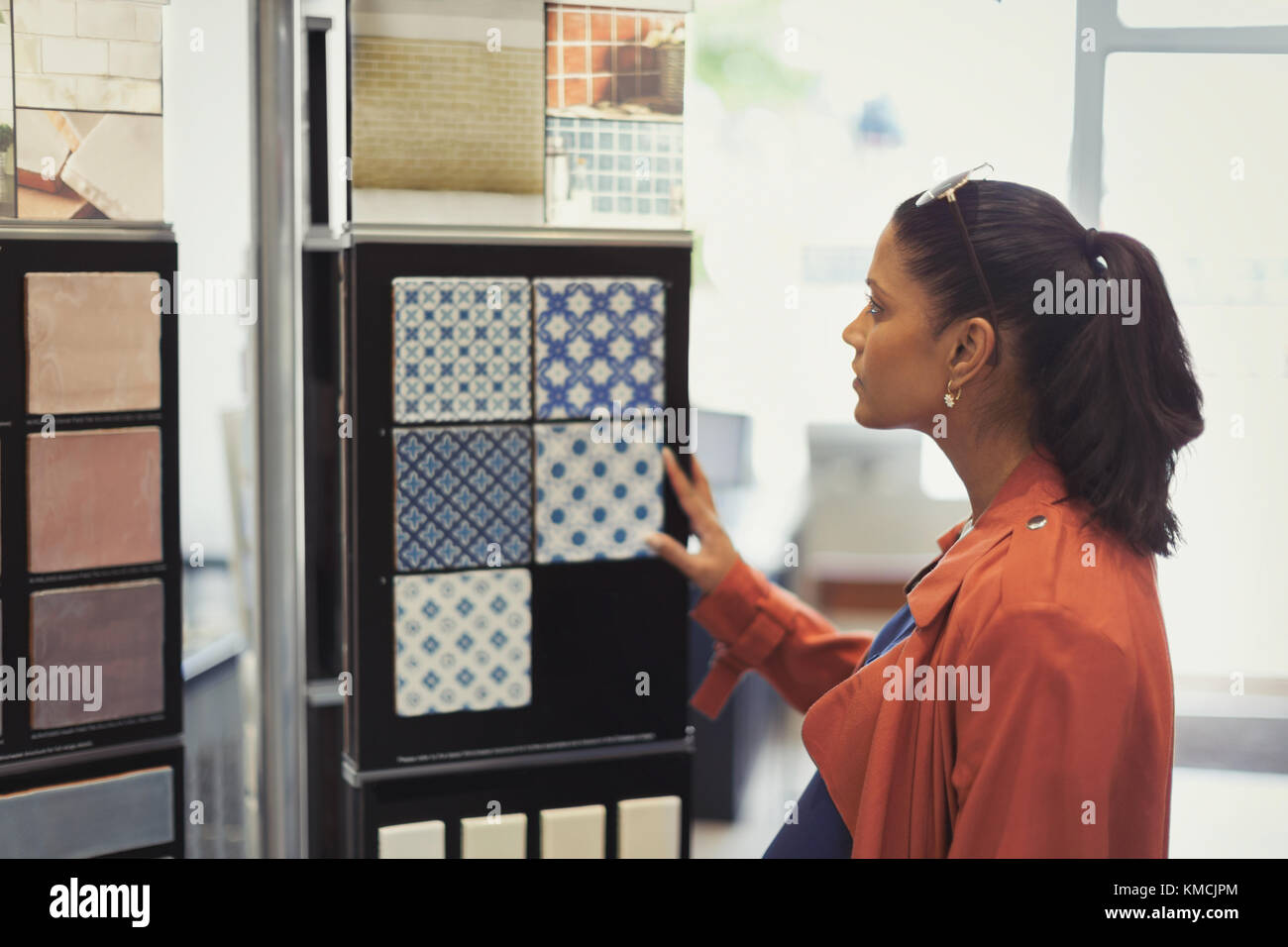 Mujer hojeando muestras de azulejos en la tienda de mejoras en el hogar Foto de stock