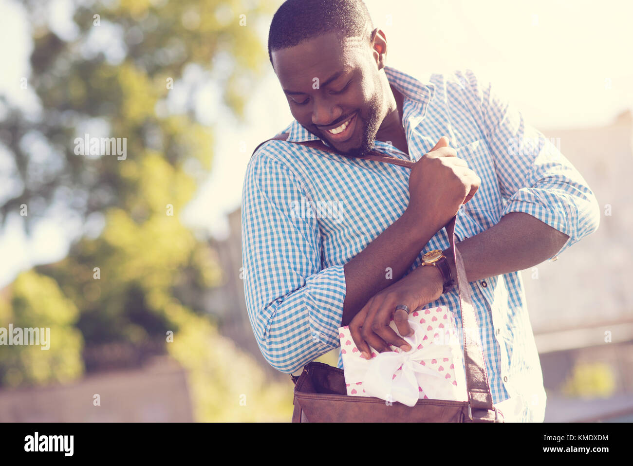 Encantado afro americana hombre haciendo un regalo en su bolsa Foto de stock