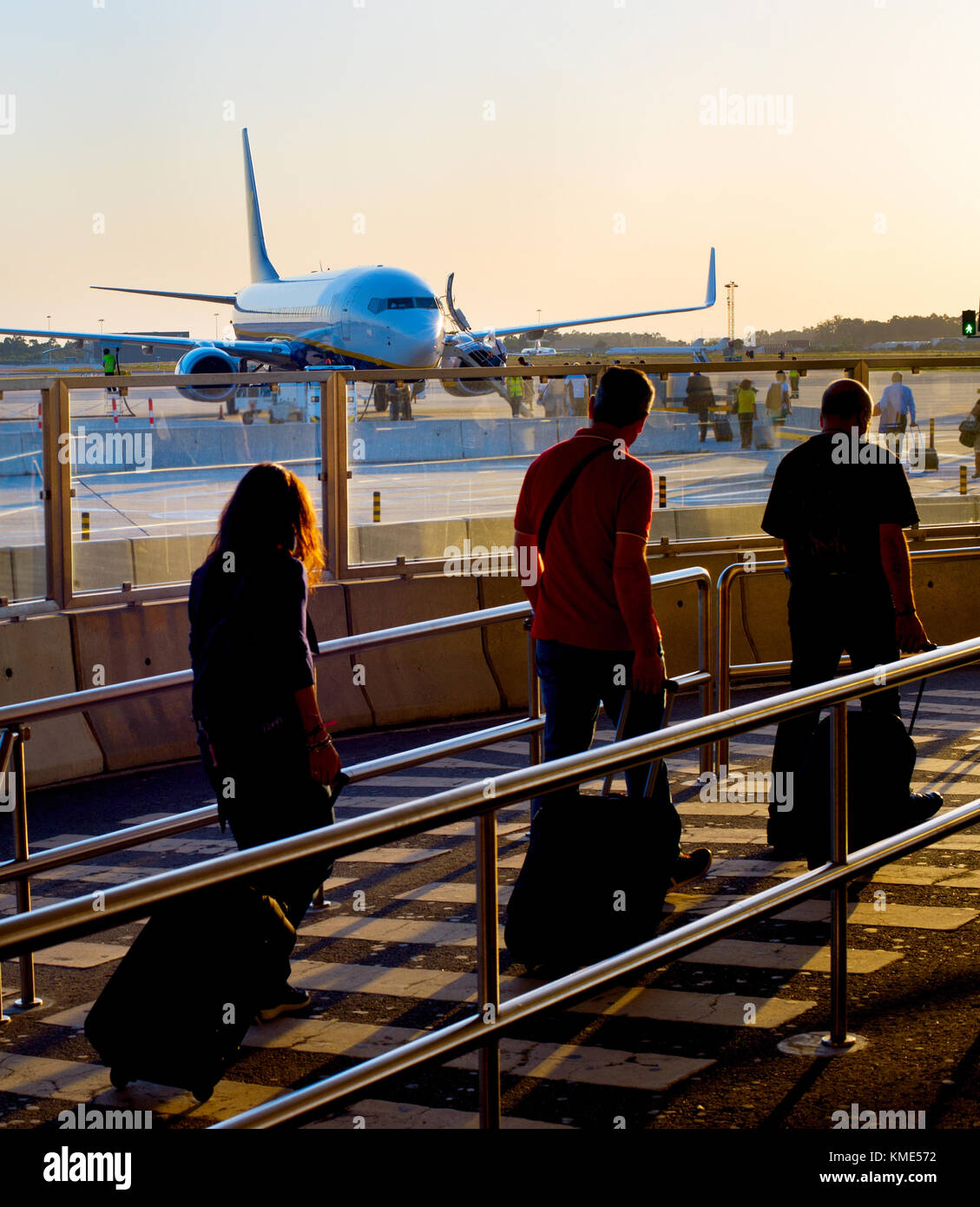 Los pasajeros de avión en un aeropuerto de embarque al atardecer Foto de stock